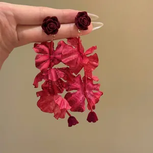 Macro detail of retro red multi-layered fabric flower drop earrings with velvet rose studs