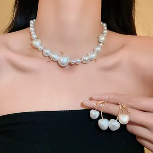 Detailed view of elegant cherry-shaped pearl necklace and matching earrings on model