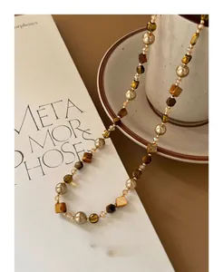 Close-up of irregular tiger eye and pearl beaded necklace with elegant earth tones