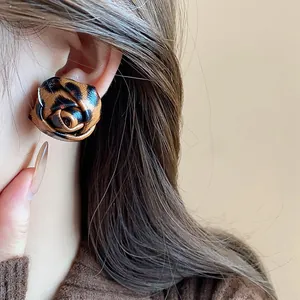Detalle de pendiente de rosa con estampado de leopardo y aguja de plata para otoño