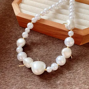 Close-up detail of a French style necklace featuring white pearls and gold cherry accents.
