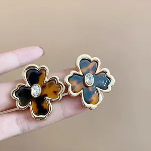 Primer plano de pendientes de flores vintage con resina de carey y bordes dorados