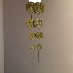 Close-up of vintage gold circular disc tassel earrings with a refined textured finish