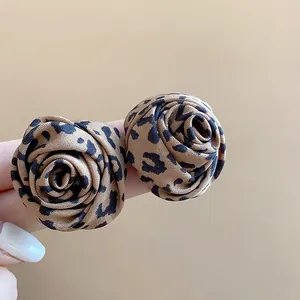 Vista detallada de los pendientes de botón con forma de rosa y estampado de leopardo