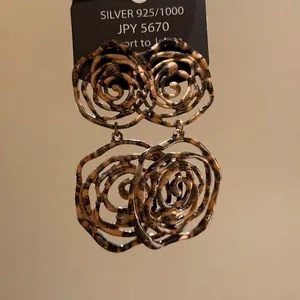 Detailed macro view of bold retro floral rose earrings featuring a unique tortoiseshell pattern