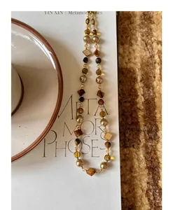 Detailed view of tiger eye stone and pearl beaded necklace in warm brown tones.
