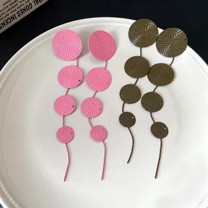Detailed view of retro textured circle tassel earrings in pink and olive colors.