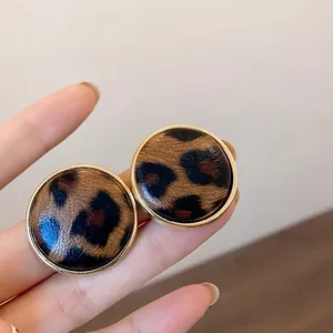 Detalle de pendientes vintage con estampado de leopardo y elegantes bordes dorados