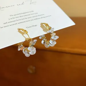Dettaglio di orecchini a cerchio placcati oro 18k con cristalli trasparenti.