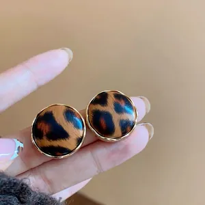 Vista detallada de pendientes de botón con estampado de leopardo y elegante borde dorado
