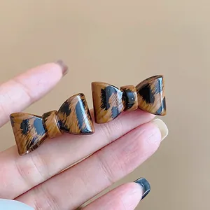 Detalle de pendientes de lazo con estampado de leopardo vintage y acabado brillante