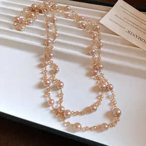 Dettaglio della collana di perle color champagne e cristalli a strati su un vassoio bianco.