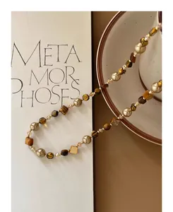 Macro view of Maillard style necklace with irregular tiger eye stones and pearls.