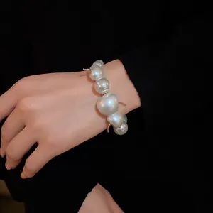 Close-up detail of an elegant baroque pearl bracelet with irregular white beads and gold accents