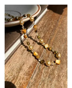Detail of beaded necklace featuring irregular tiger eye stones and lustrous pearls
