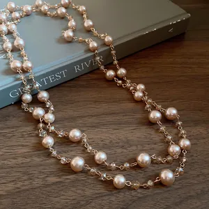 Primo piano dettagliato di una collana di perle color champagne e cristalli su libro