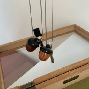 Détail de pendentifs en forme de gland en bois et métal suspendus sur une boîte miroir.