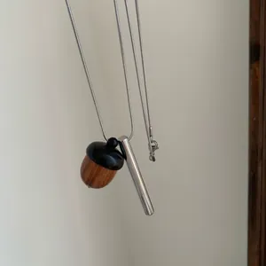 Vue détaillée d'un pendentif gland en bois et cylindre en argent sur une chaîne serpent