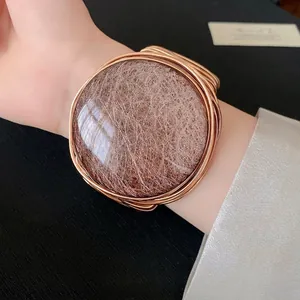 Elegante pulsera rígida vintage de resina tejida en oro rosa con un diseño minimalista