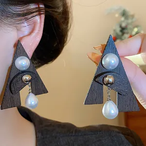 Dettaglio di orecchini geometrici a triangolo in legno con eleganti perle a goccia da donna