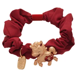 Chouchou rouge avec une adorable breloque de cheval doré pour apporter la prospérité