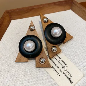 Dettaglio orecchini etnici a triangolo in legno con perle e perni in argento