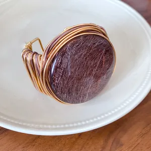 Detalle de un brazalete retro de resina redonda envuelto en alambre en un plato blanco.