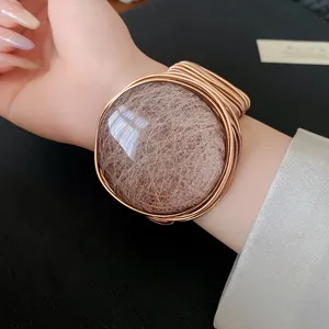 Vista detallada de un elegante brazalete abierto de resina tejida circular en la muñeca