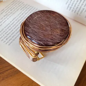 Primer plano de un brazalete retro de resina redonda con diseño envuelto en alambre dorado