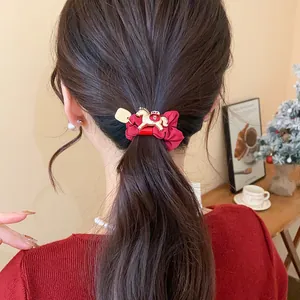 Détail d'un chouchou rouge vif avec une breloque décorative en forme de cheval doré.
