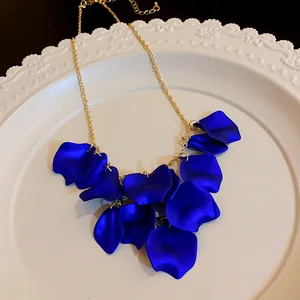 Gros plan d'un collier à pompons en pétales bleu foncé sur une assiette blanche décorative