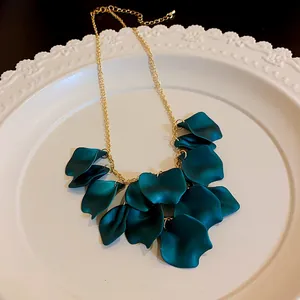 Détail d'un collier chaîne dorée avec des breloques pétales mats bleu sarcelle foncé