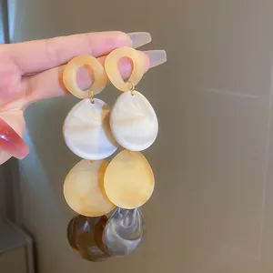Close-up detail of vintage style yellow and white marbled resin teardrop drop earrings