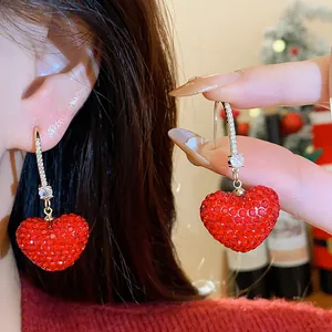 Detailed close-up of sparkly red heart-shaped earrings with full zircon embellishments