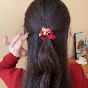 Vue détaillée d'un chouchou en velours rouge avec un pendentif cheval doré sur cheveux
