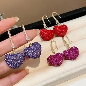 Detail view of sparkling heart-shaped earrings with purple, red, and pink crystals.