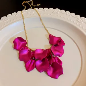 Détail d'un pendentif en forme de pétale magenta sur un collier en chaîne plaqué or
