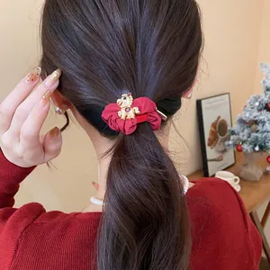 Gros plan d'un chouchou festif en tissu rouge avec une breloque cheval dorée sur une queue