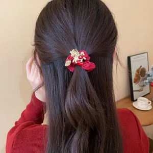 Chouchou rouge avec breloque cheval dorée sur cheveux longs pour look festif