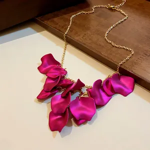 Gros plan sur les pétales en tissu magenta vif d'un collier chaîne doré élégant
