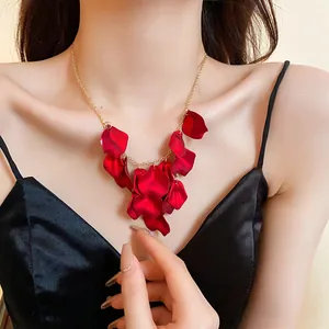Gros plan d'un collier élégant à glands de pétales rouges sur une chaîne dorée.