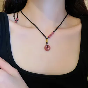 Detailed shot of a pink crystal donut pendant necklace with a black hand-woven cord.