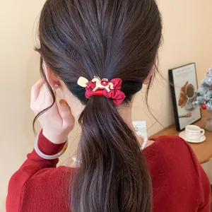 Vue détaillée d'un chouchou rouge avec un charm cheval doré dans les cheveux