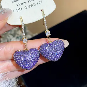 Close-up of shimmering purple heart earrings with sparkling cubic zirconia pavé setting