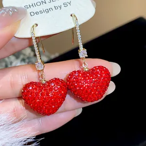 Close-up of sparkling red rhinestone heart earrings with gold hooks