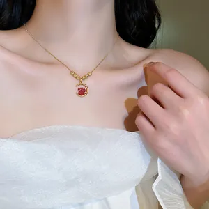 Macro view of gold crescent moon necklace with a red rabbit pendant worn by a model