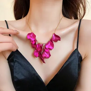 Vue détaillée d'un collier avec des glands en pétales rose fuchsia sur une chaîne dorée.