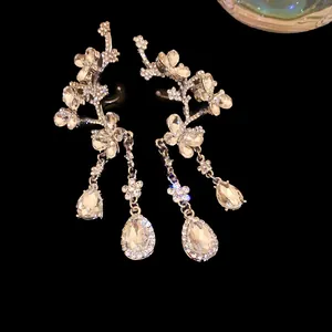 Detail of silver needle earrings with rhinestone butterfly, flower, and teardrop charms