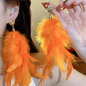 Detailed view of vibrant orange feather tassel earrings with textured gold studs