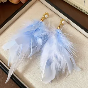 Elegant blue and white feather tassel earrings with pearl studs displayed in a jewelry box